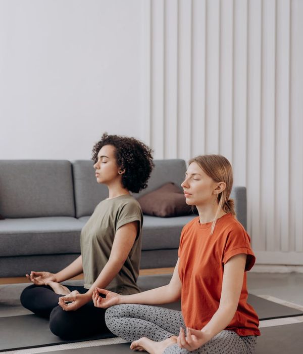 Woman performing a gentle yoga pose in a bright, minimalist room.